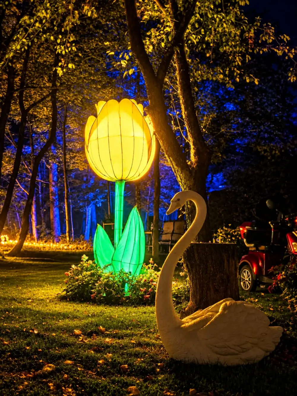 Une fleur géante lumineuse et un cygne décoratif dans le boisé